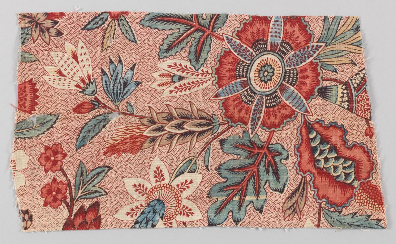 A fragment of cotton printed in red, blue and brown with large stylised flowers, leaves and a feathery spray on a ground of fine red dots.