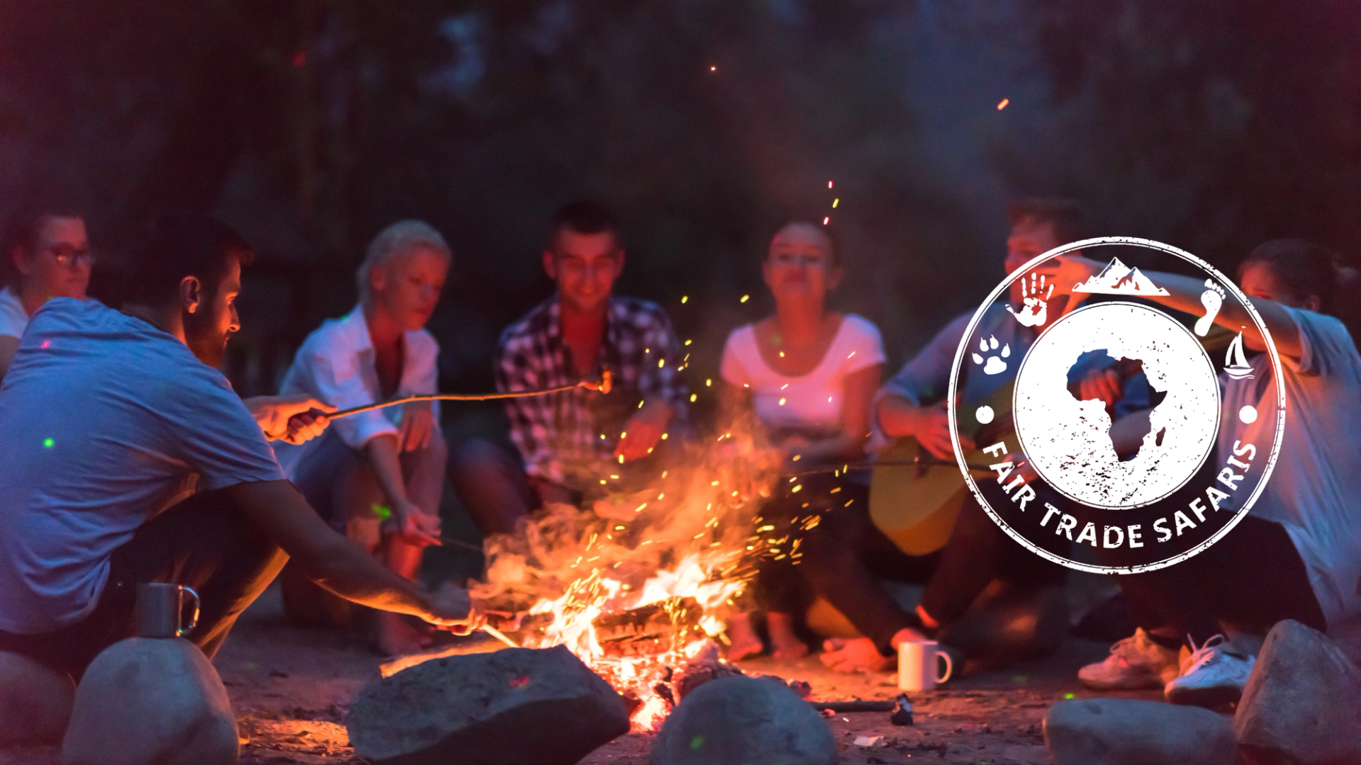 Group of friends gathered around a campfire at night, roasting marshmallows and enjoying time together outdoors, with the Fair Trade Safaris logo displayed on the right.