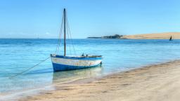 Traditional dhow anchored in shallow turquoise water along a sandy beach in Mozambique