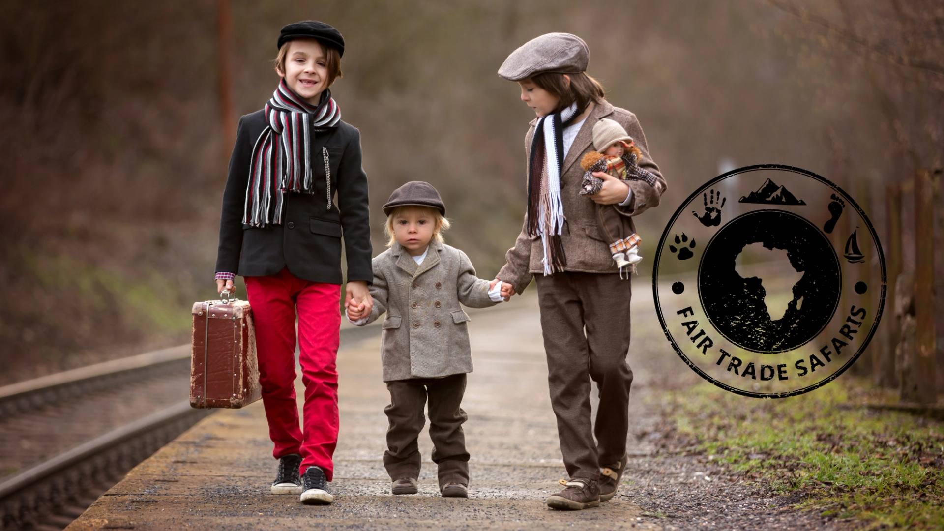 Three children in vintage-style outfits walking hand in hand along a railway platform, one carrying a suitcase and another holding a teddy bear, with the Fair Trade Safaris logo displayed on the right.