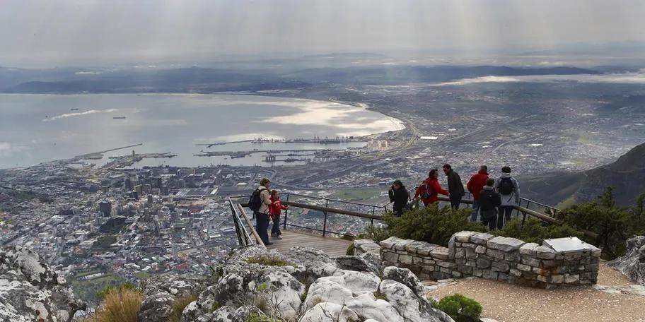Travelers enjoying panoramic views over Cape Town and Table Bay from the summit of Table Mountain, South Africa