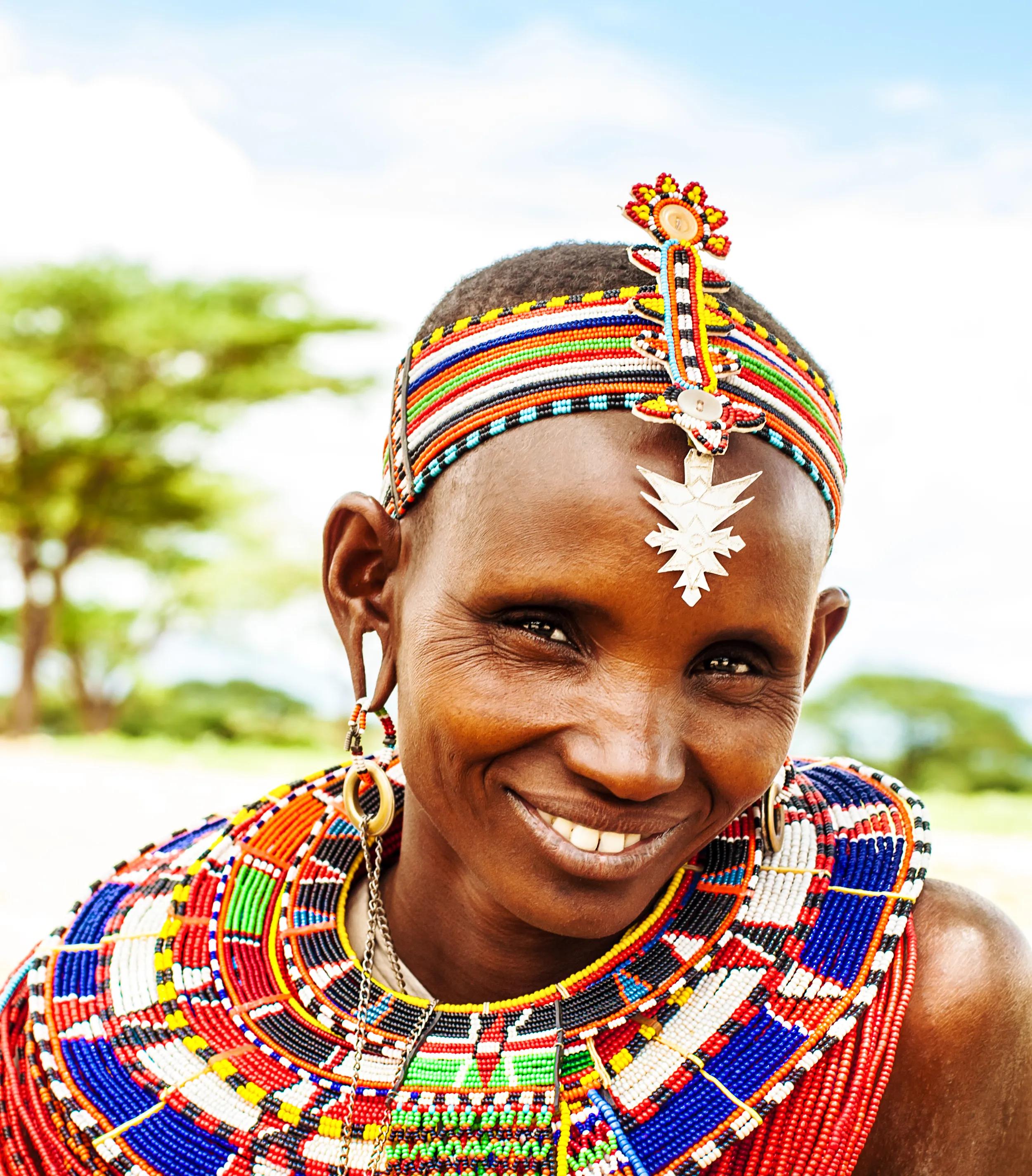 Smiling Maasai woman in traditional beaded attire and jewelry, representing Maasai culture in Kenya