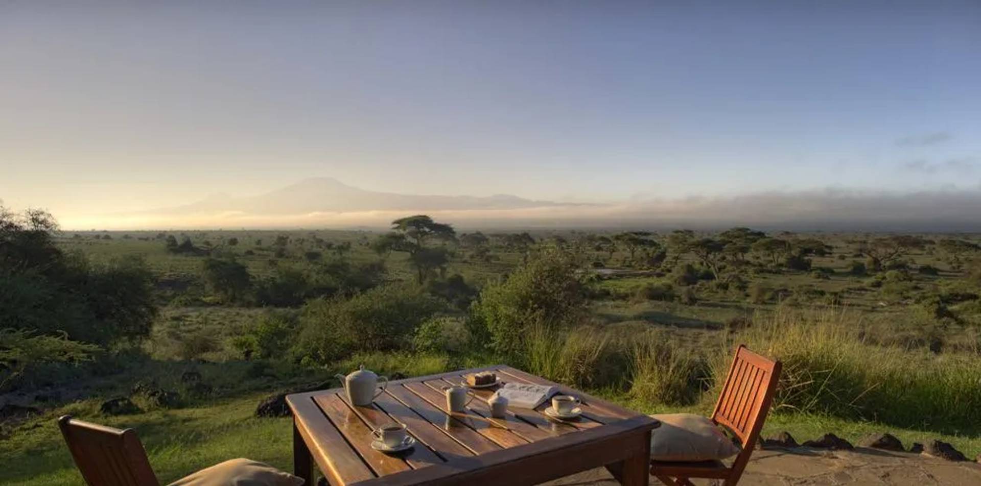 Breakfast table set on a terrace overlooking the African savanna at sunrise