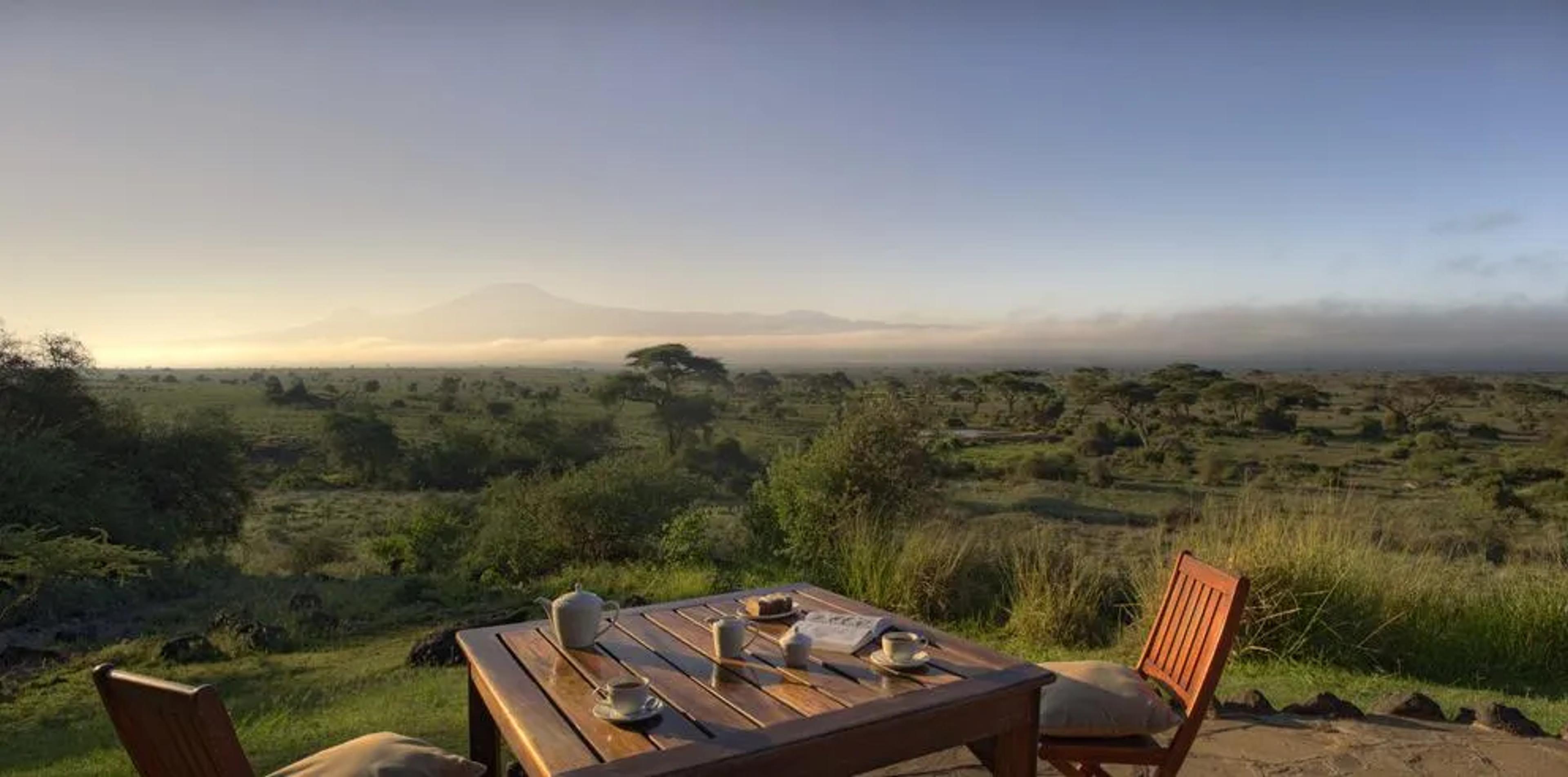 Breakfast table set on a terrace overlooking the African savanna at sunrise