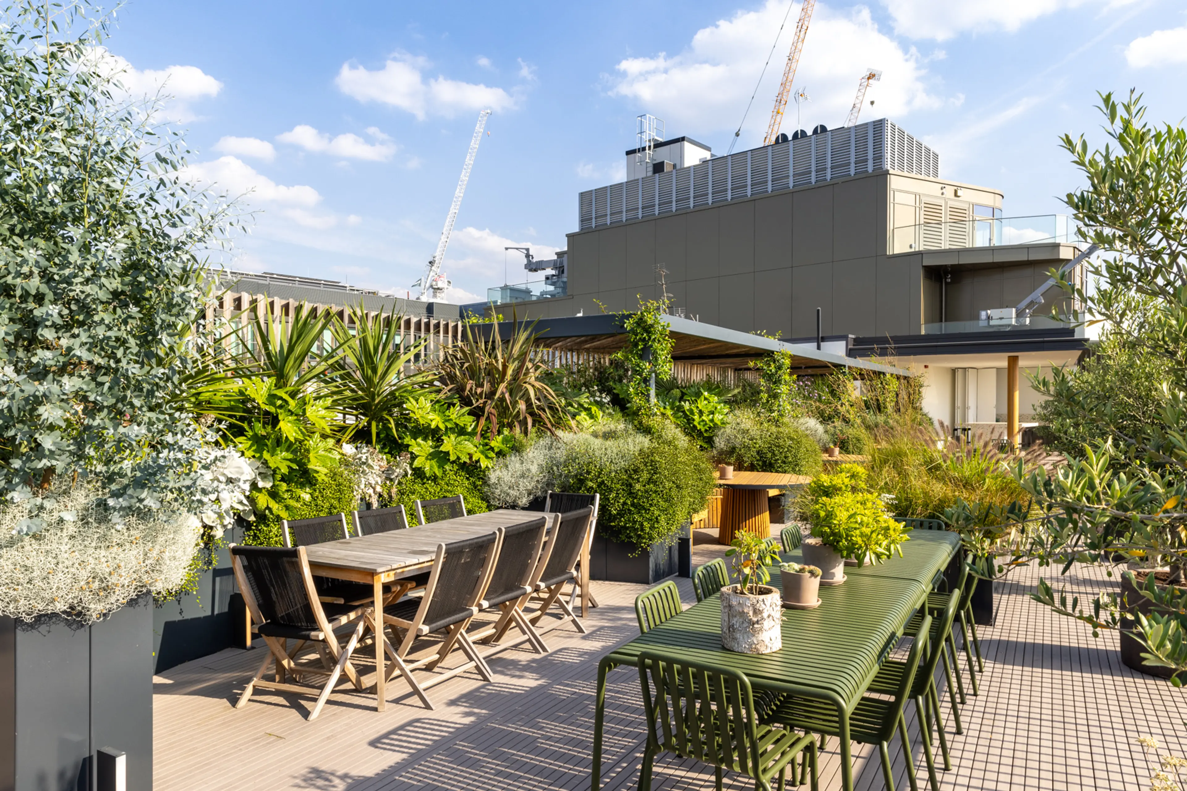 Outdoor dining on a verdant rooftop terrace with city views.