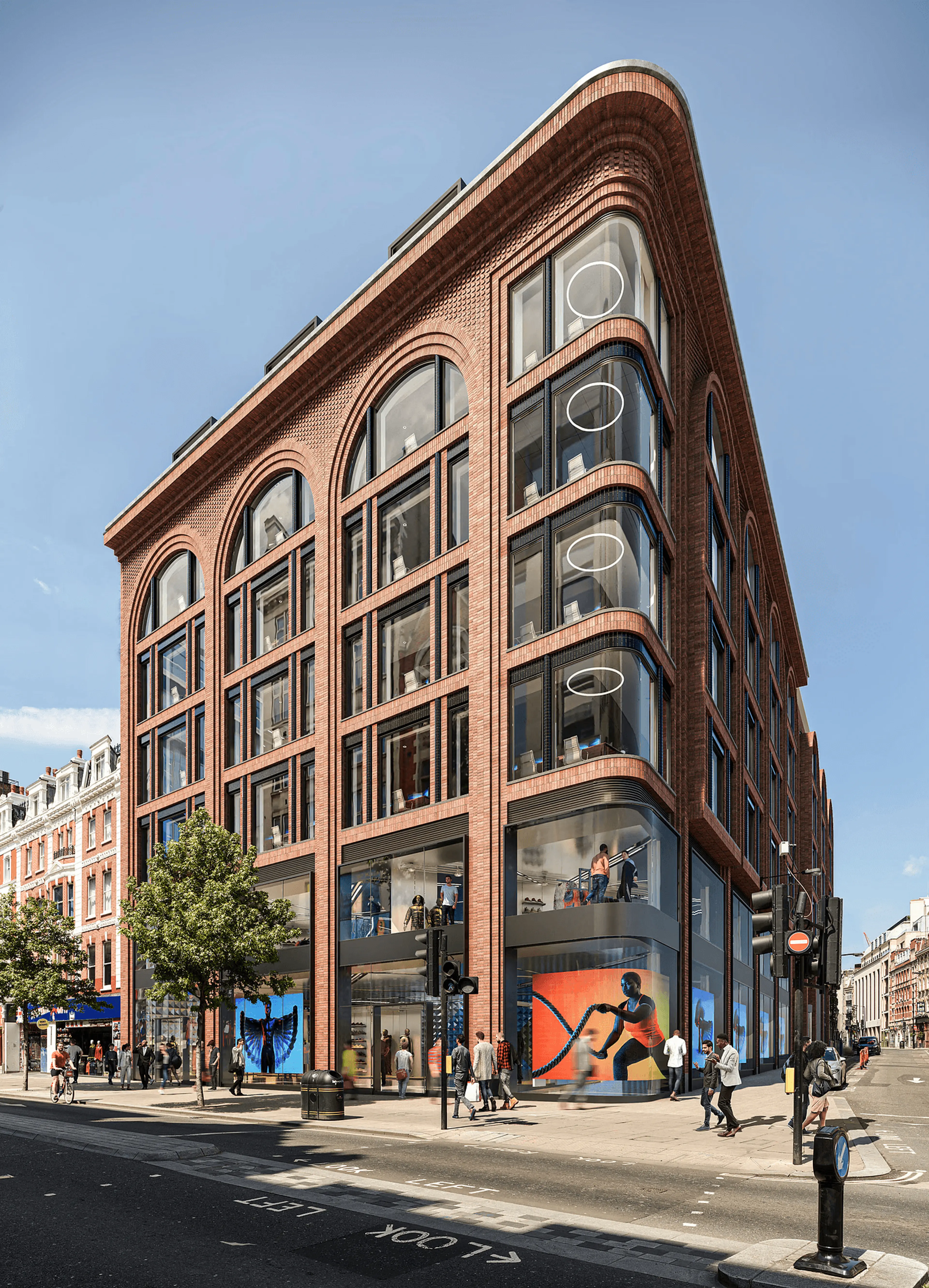 A modern brick building with large arched windows and curved glass at its corner, featuring ground-floor shops, on a sunny city street with pedestrians.