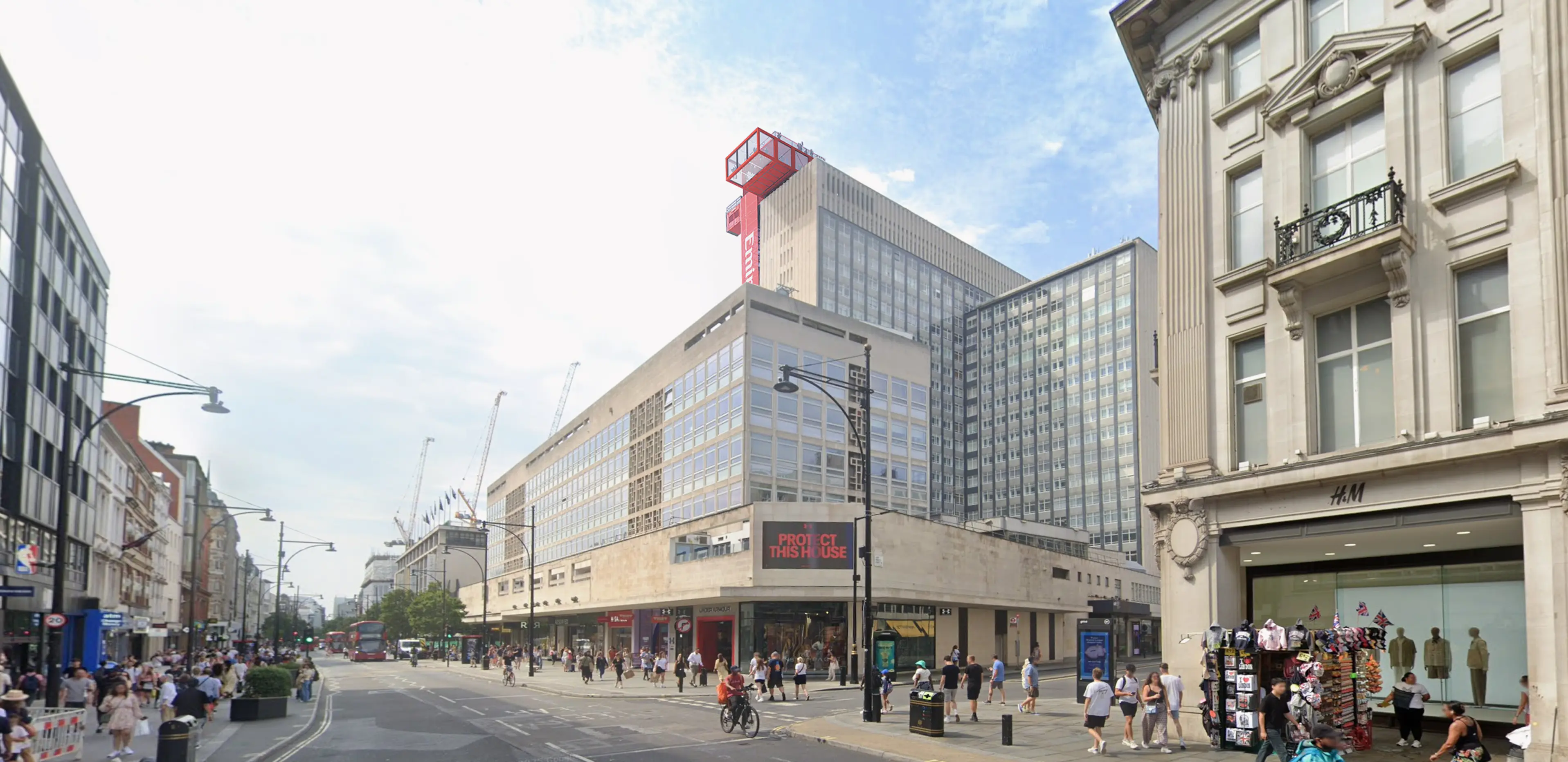 Bustling city street with large retail buildings, pedestrians, and a distinctive red structure on the roof of a prominent department store.
