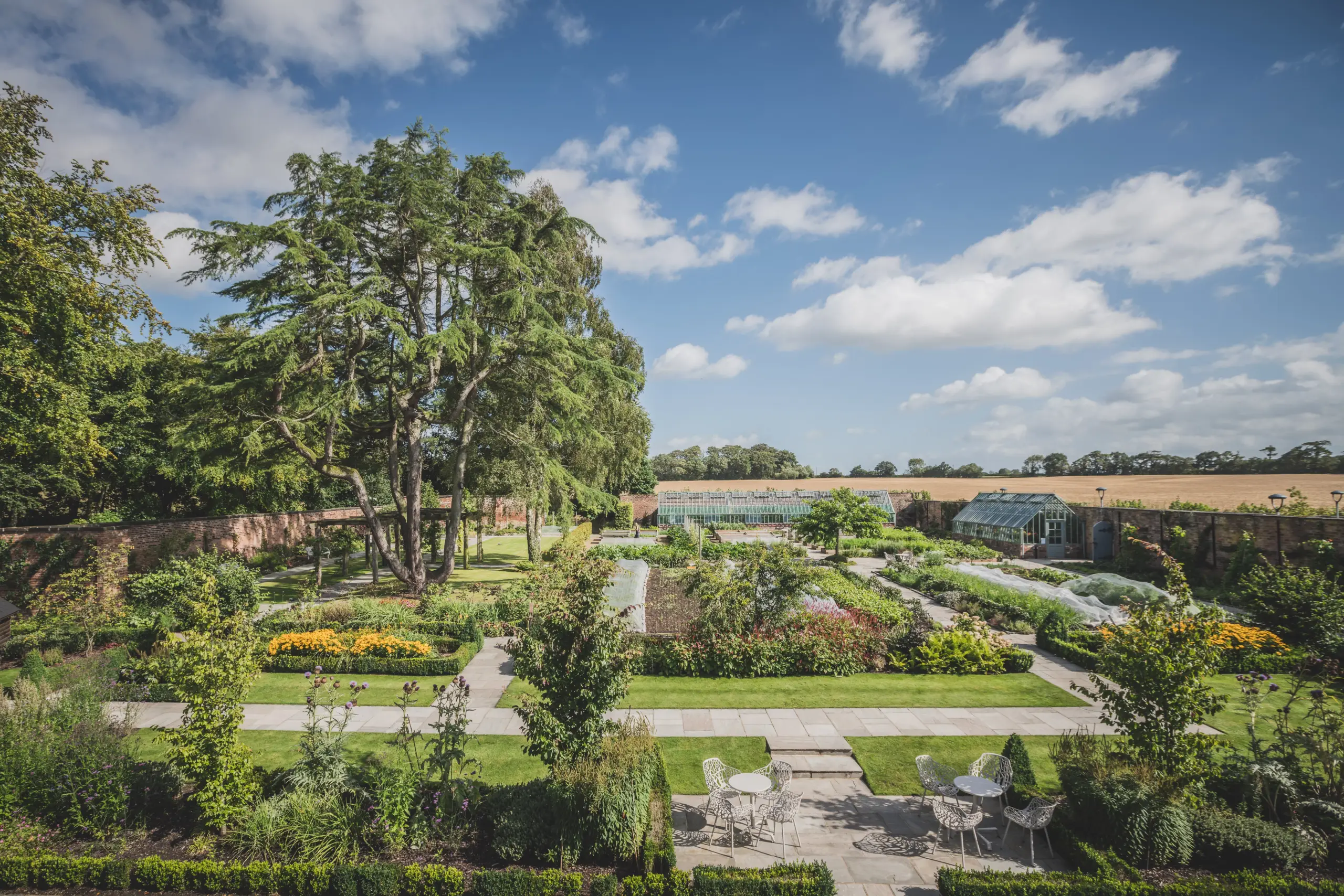 The walled kitchen gardens and glasshouses at Moor Hall, with countryside views beyond