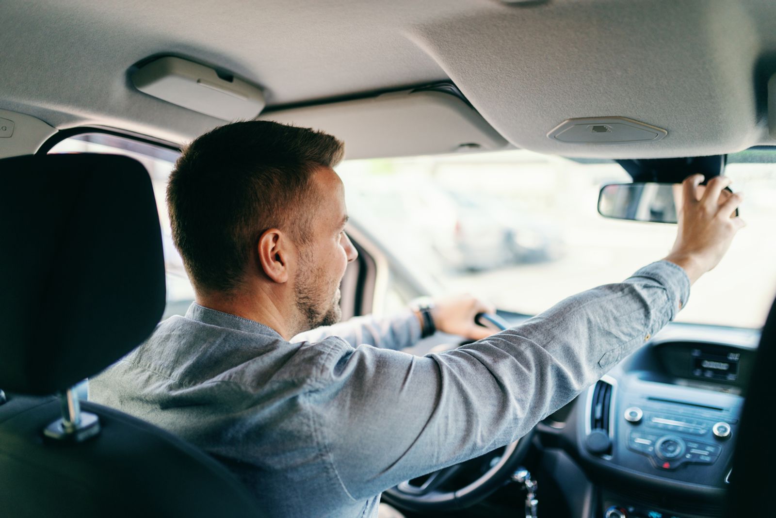 En mann som justerer inn speilene i bilen etter å ha lest om oppmerksomhet i trafikken.