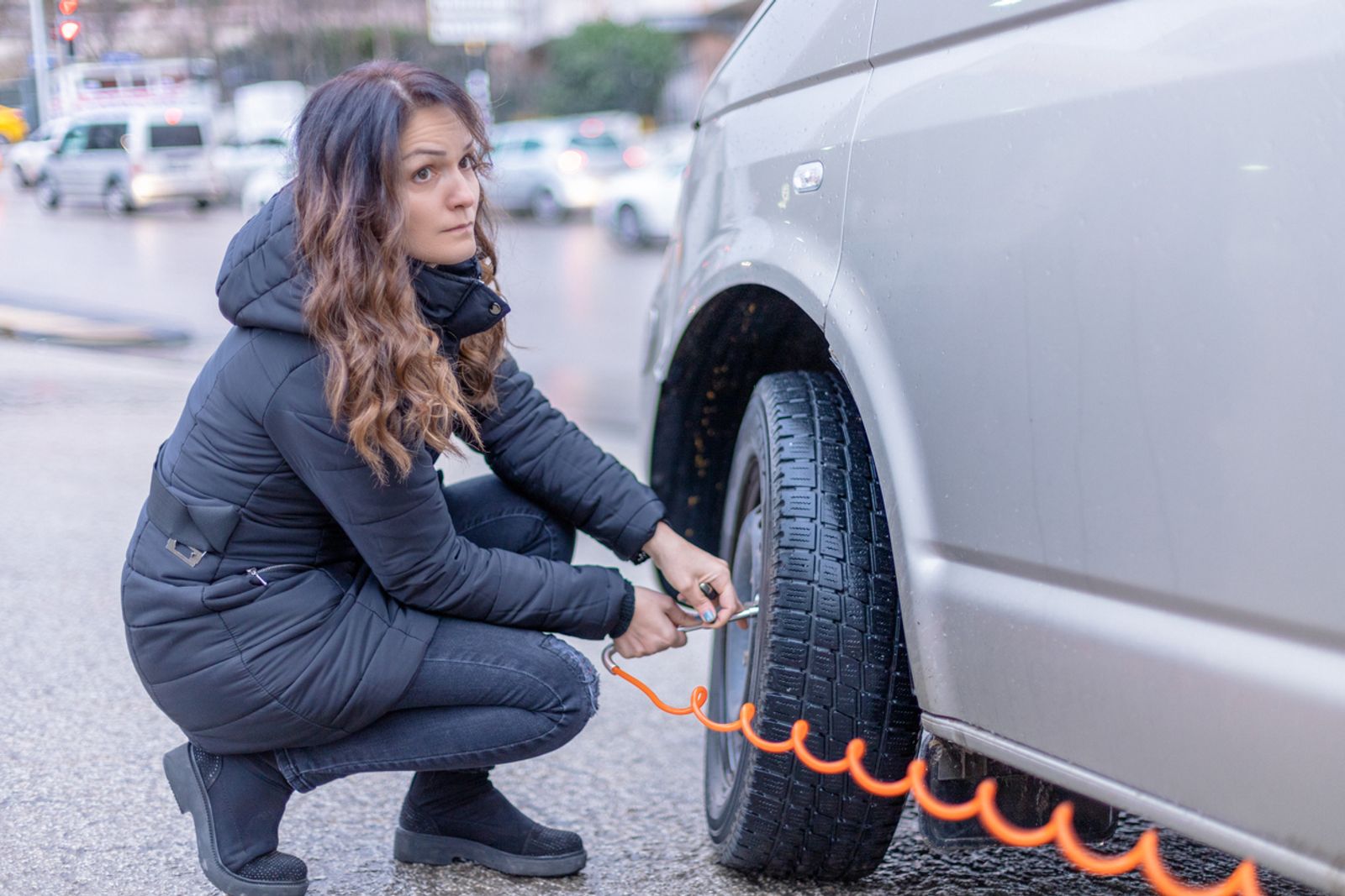 Ei dame som sitter på huk og sjekker lufttrykket i dekket på bilen sin.