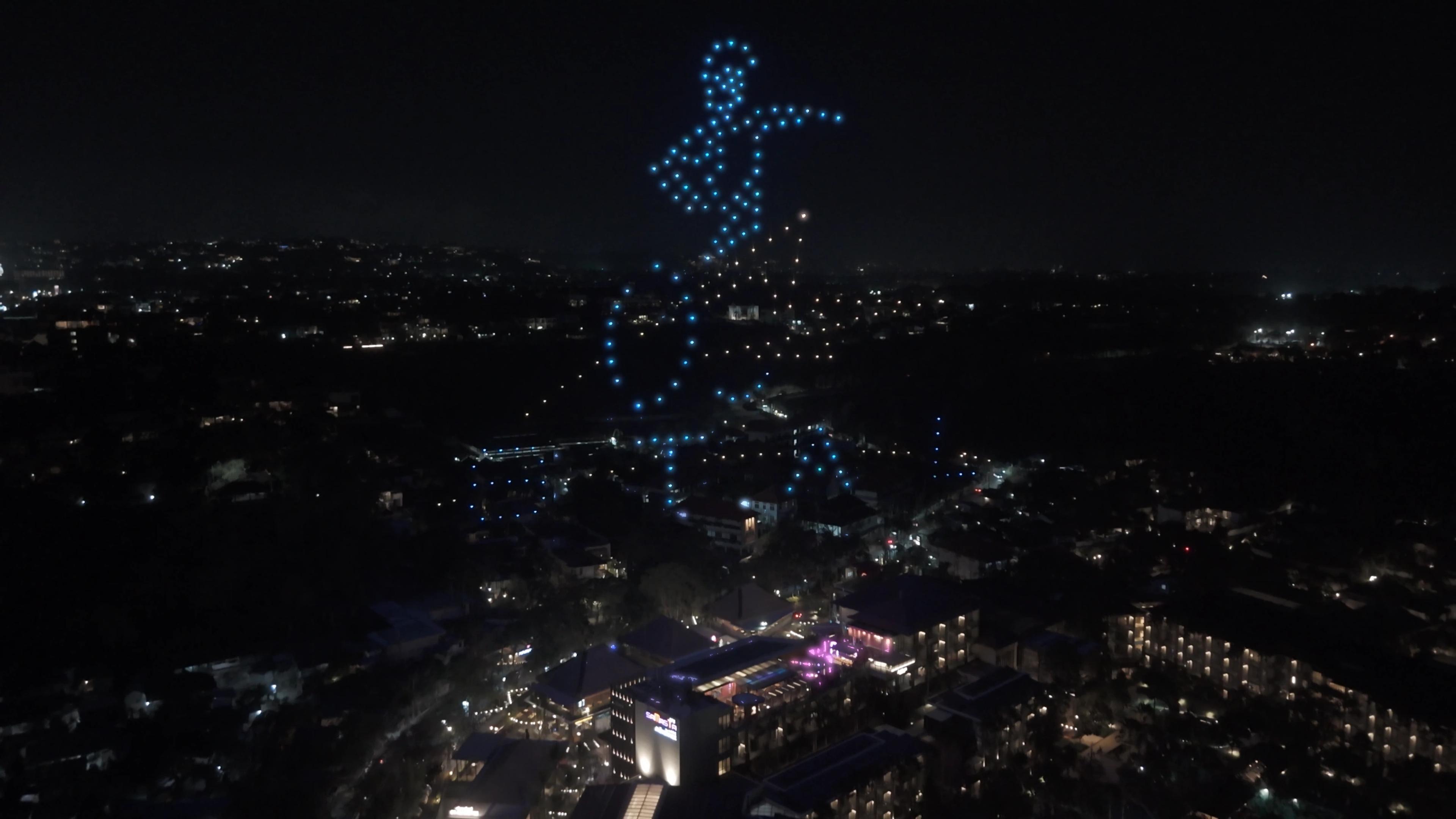 Siluet peselancar dari cahaya drone biru di atas Mövenpick Jimbaran Bali.