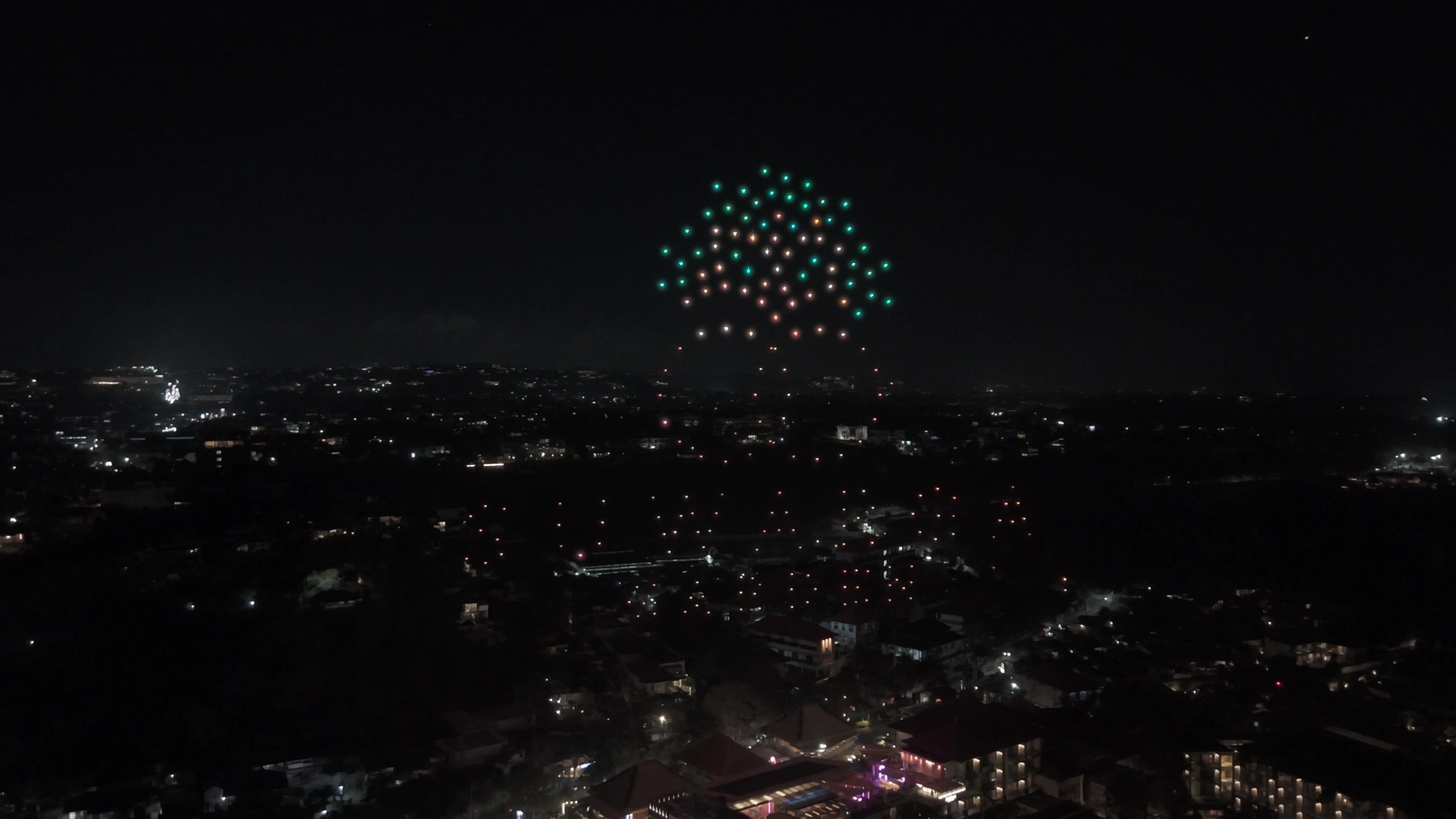 Kanopi pohon besar dari cahaya drone hijau, simbol Banyan Court di Suwarga Garden.