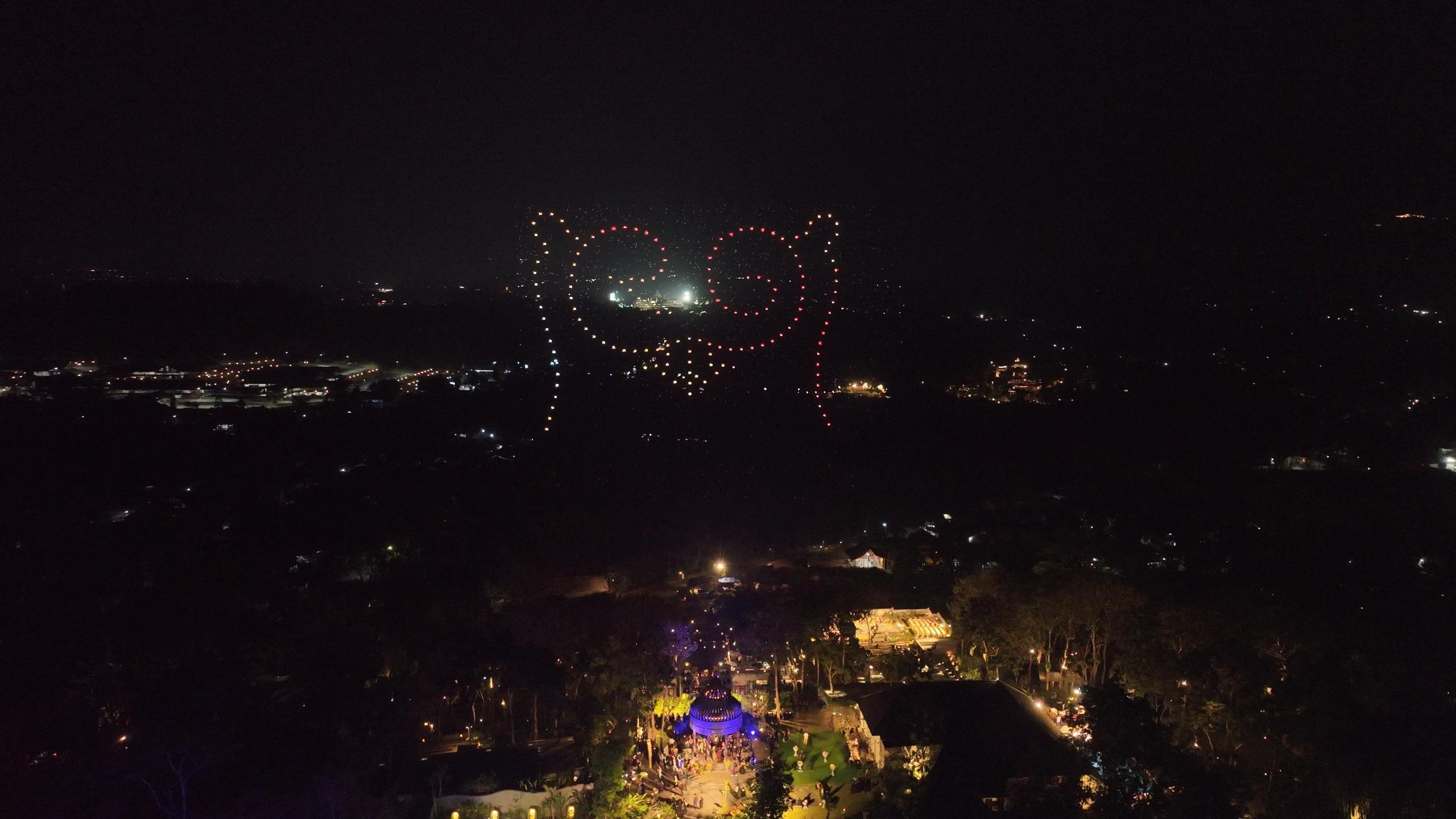 Ikon RG dari titik cahaya drone merah dan putih hangat di langit wedding Rahmani & Glen.