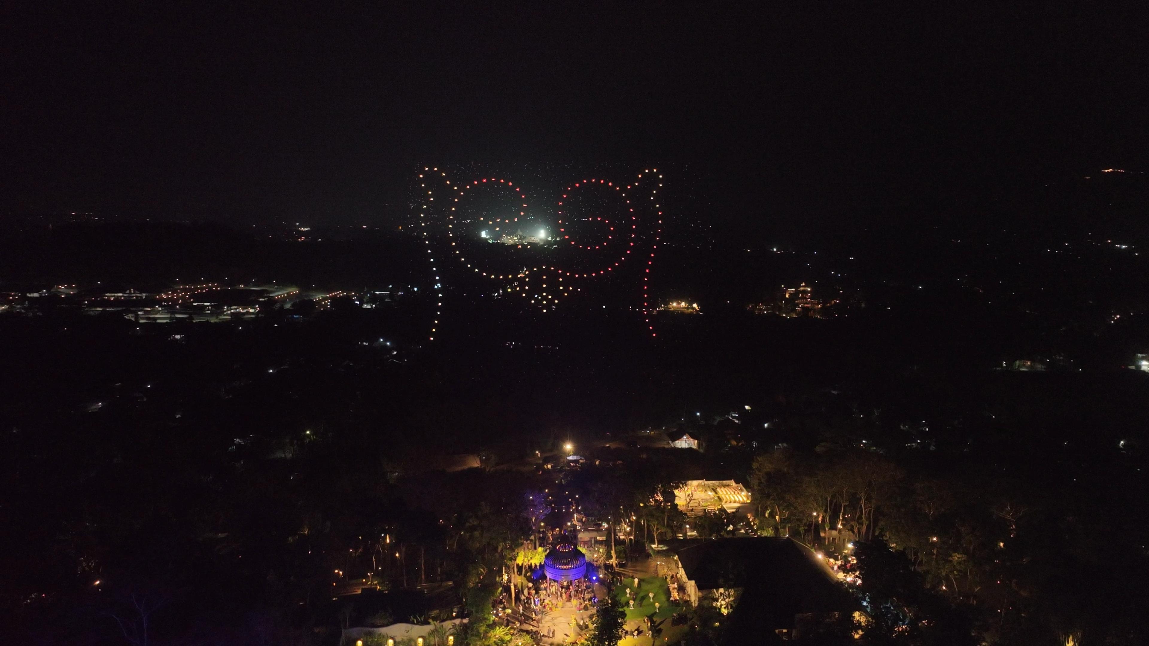 Ikon RG dari titik cahaya drone merah dan putih hangat di langit wedding Rahmani & Glen.