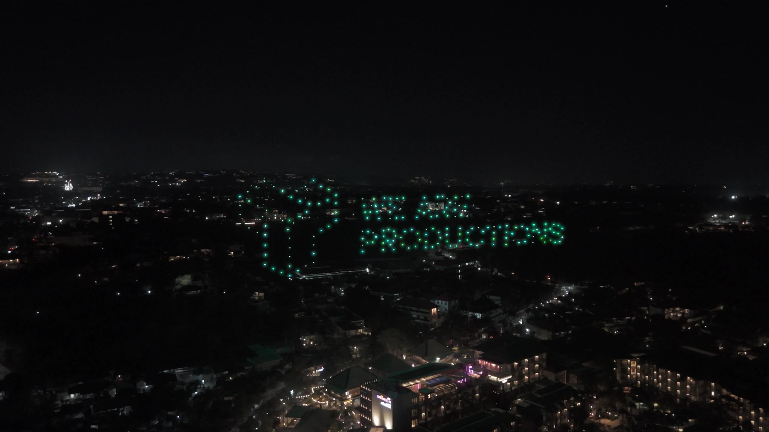 Logo We Are Productions dari cahaya drone hijau di langit Jimbaran.