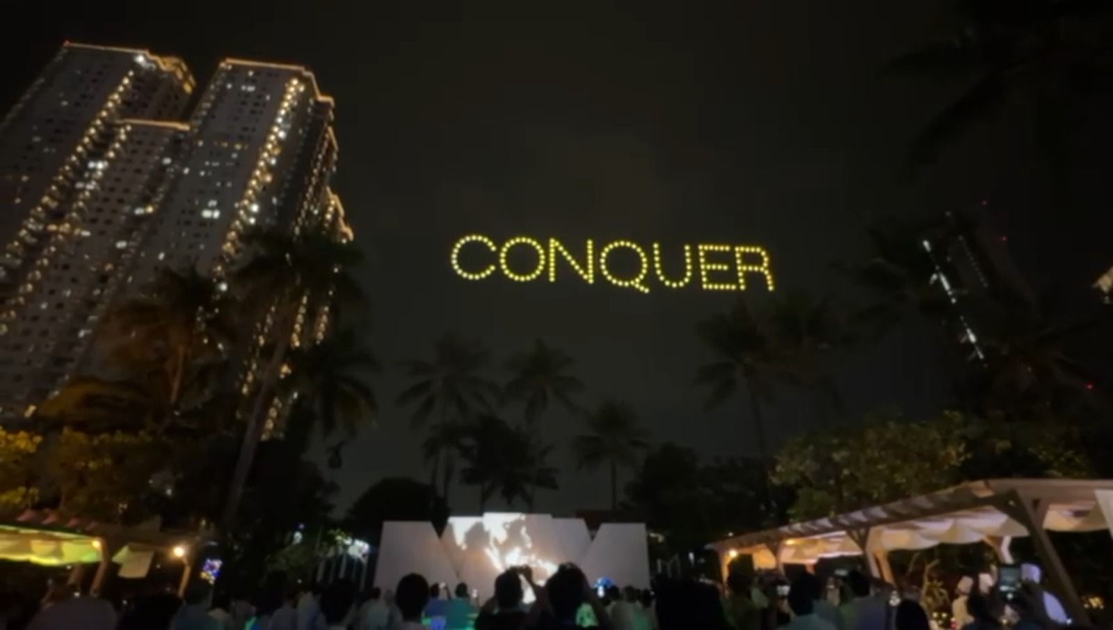 Drone light show spelling CONQUER in golden yellow letters over Shangrila Hotel Jakarta for Pertamina Lubricant National Distributor Summit 2026