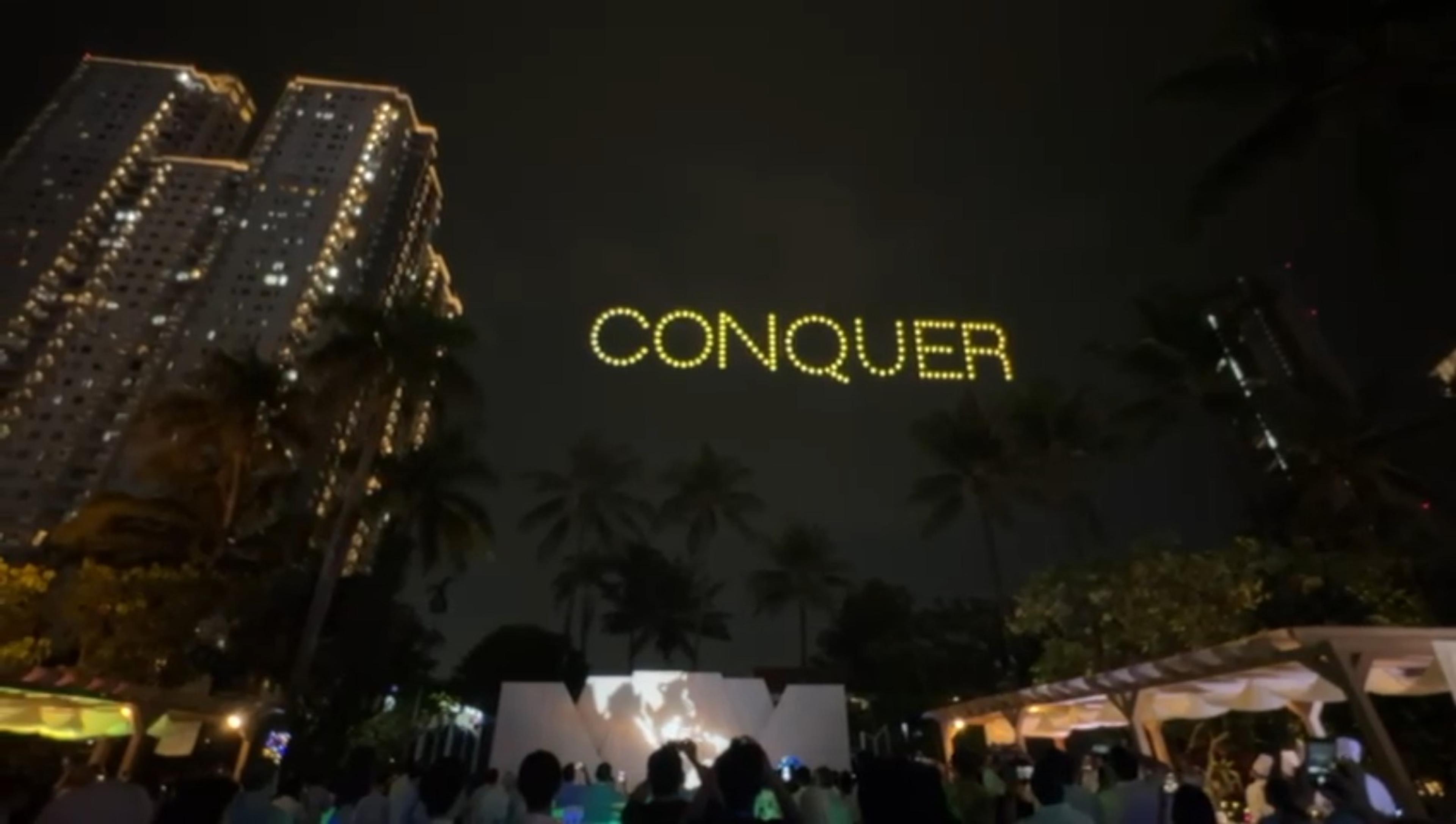 Drone light show spelling CONQUER in golden yellow letters over Shangrila Hotel Jakarta for Pertamina Lubricant National Distributor Summit 2026