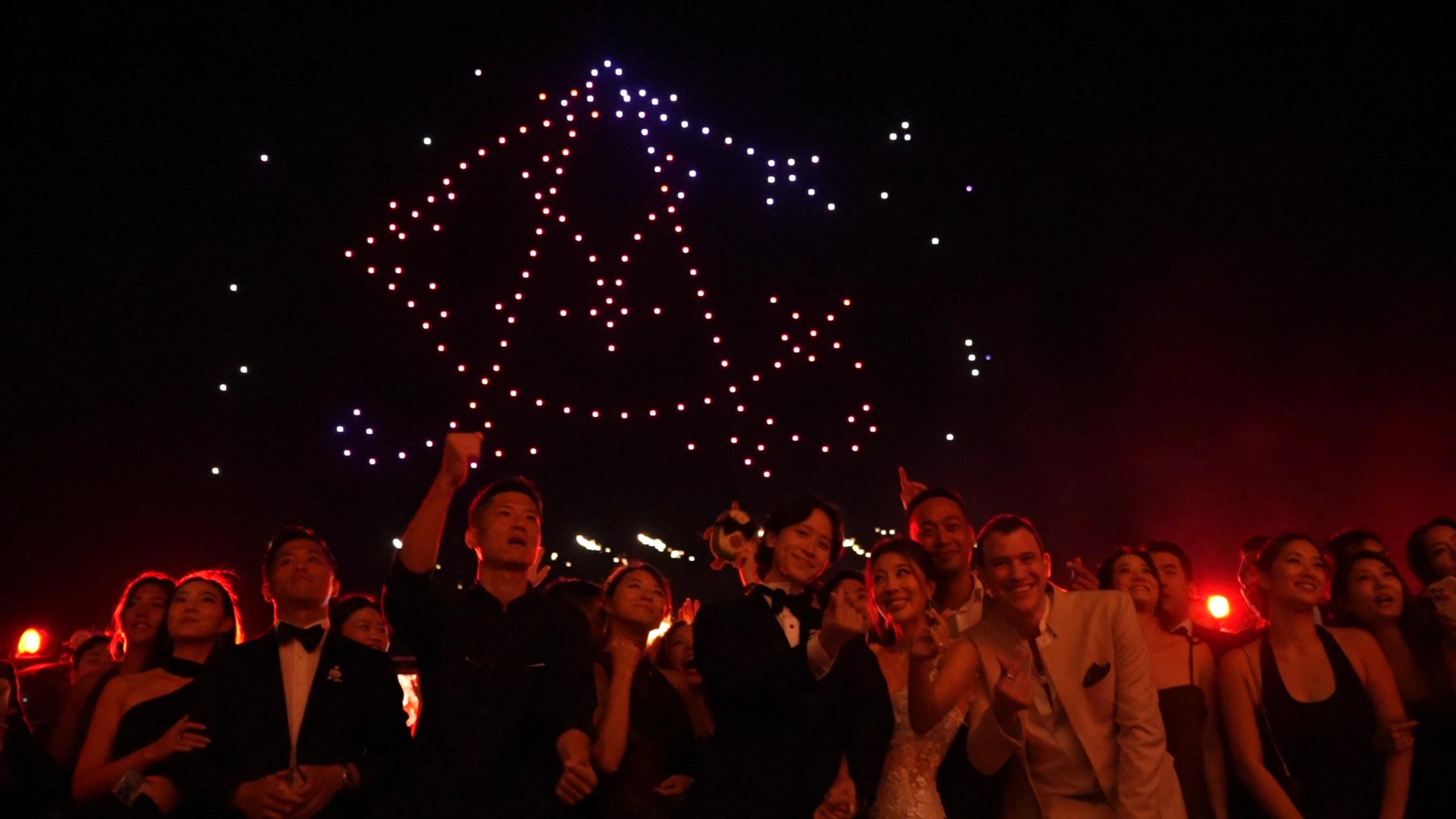 Wedding guests beneath a bell-shaped drone formation for Christina and Andrew at Alila Villas Uluwatu.