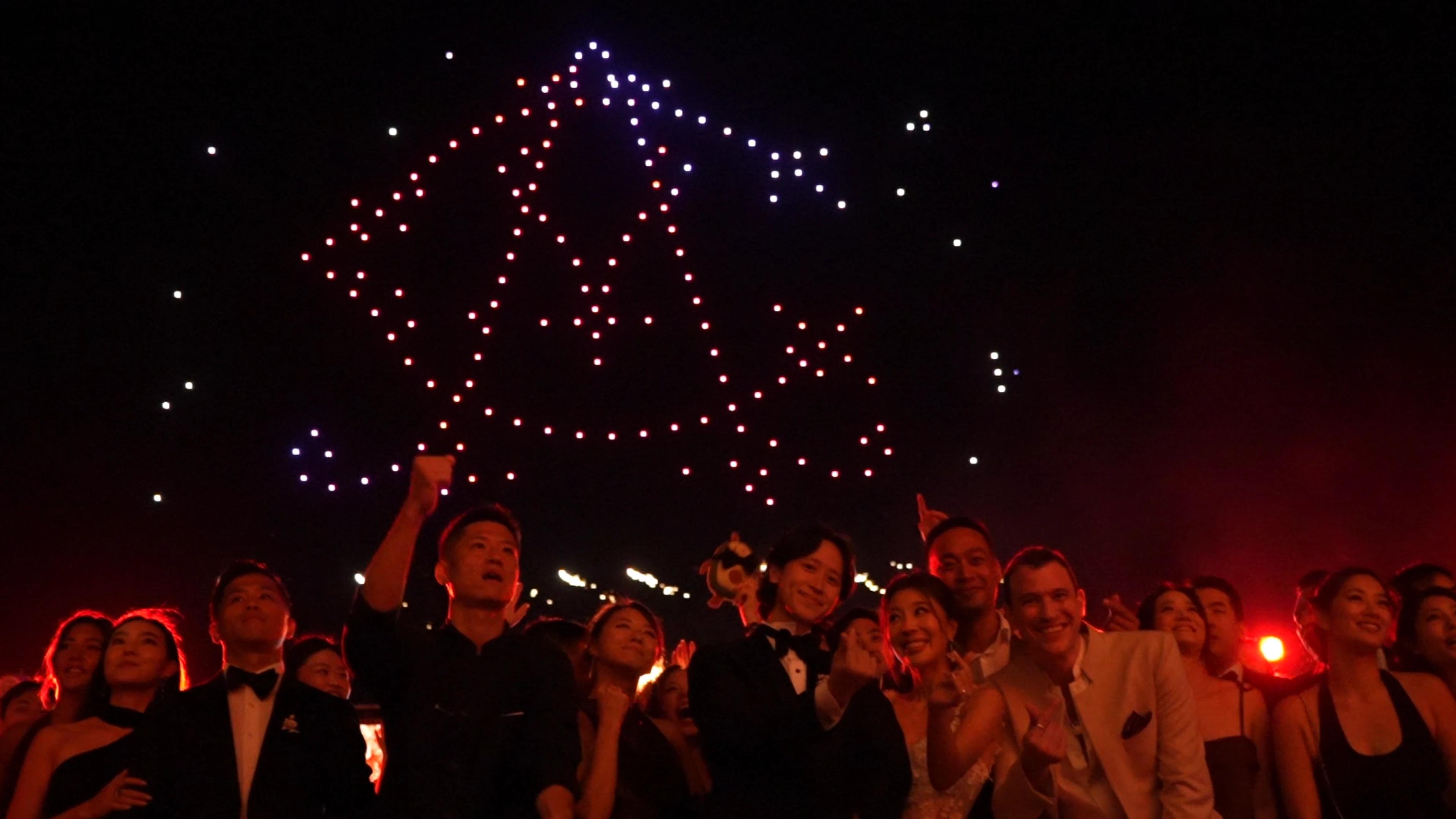 Wedding guests beneath a bell-shaped drone formation for Christina and Andrew at Alila Villas Uluwatu.