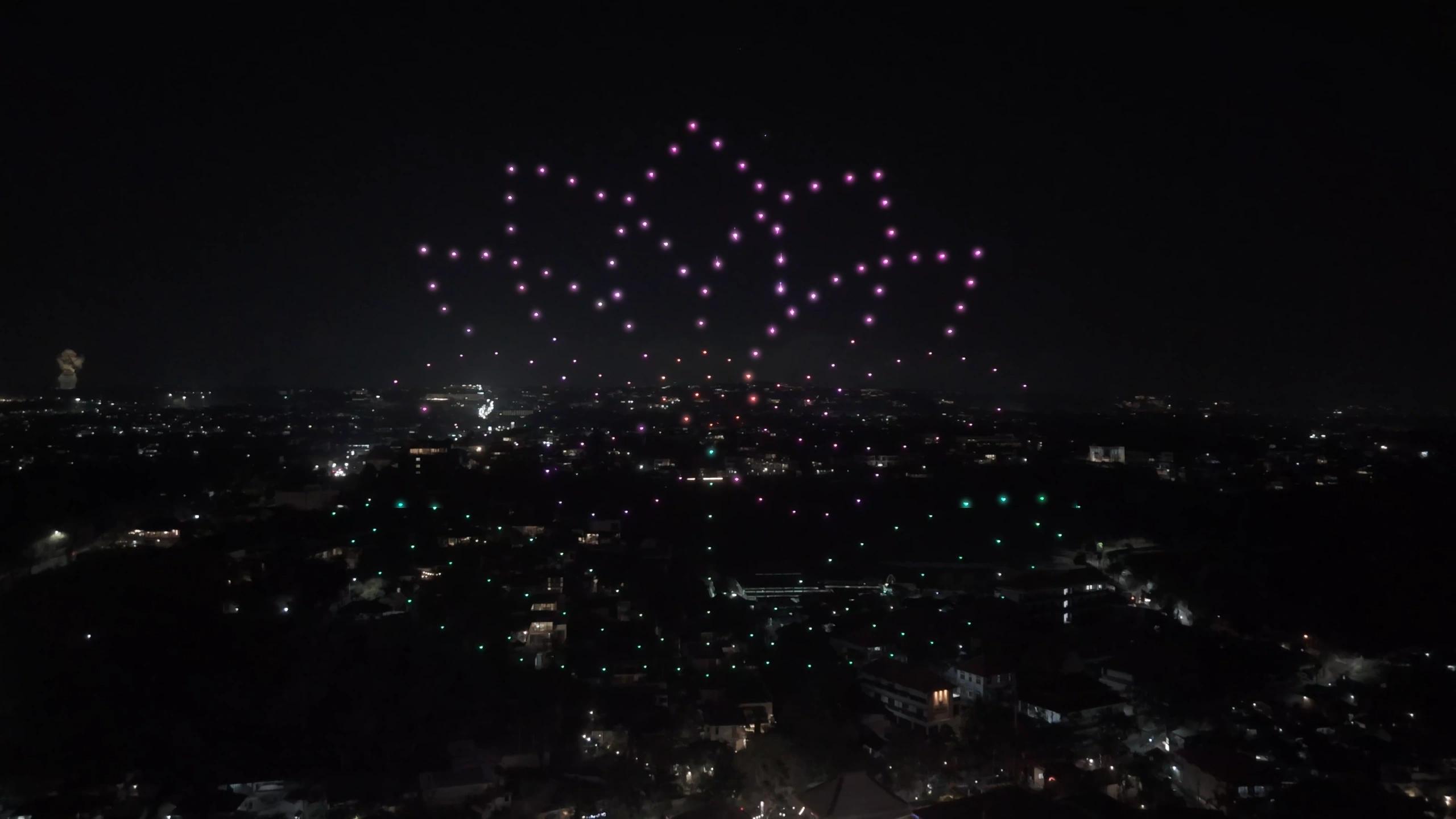 Formasi bunga teratai dari cahaya drone di atas Jimbaran saat grand opening Suwarga Garden, Mövenpick Bali.