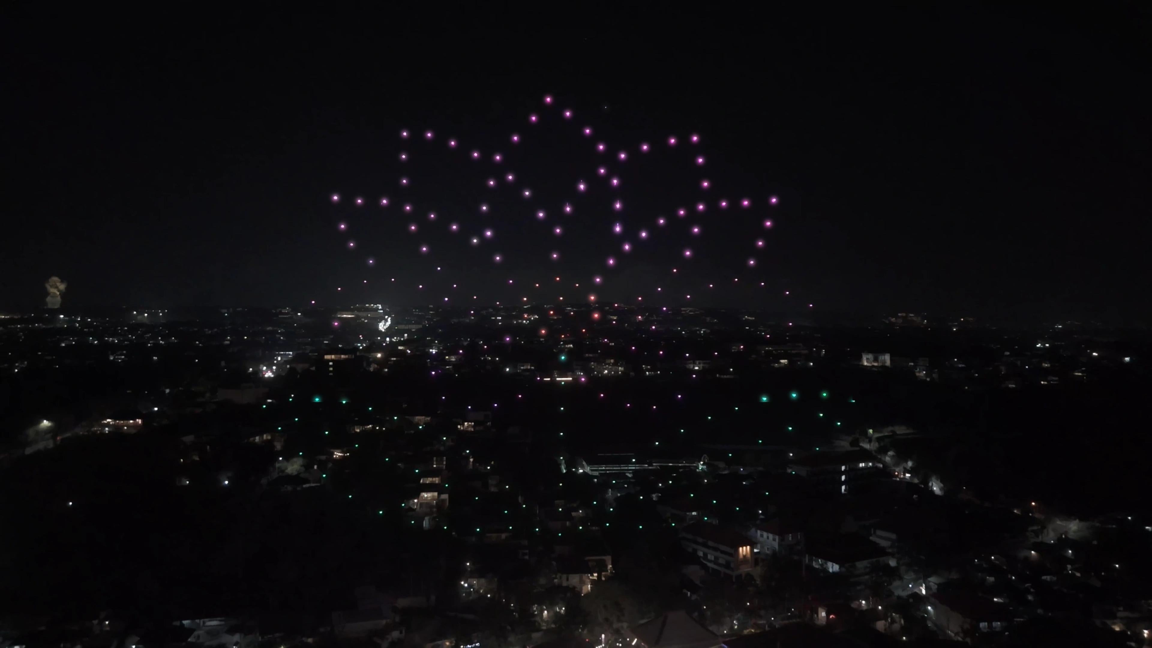 Formasi bunga teratai dari cahaya drone di atas Jimbaran saat grand opening Suwarga Garden, Mövenpick Bali.