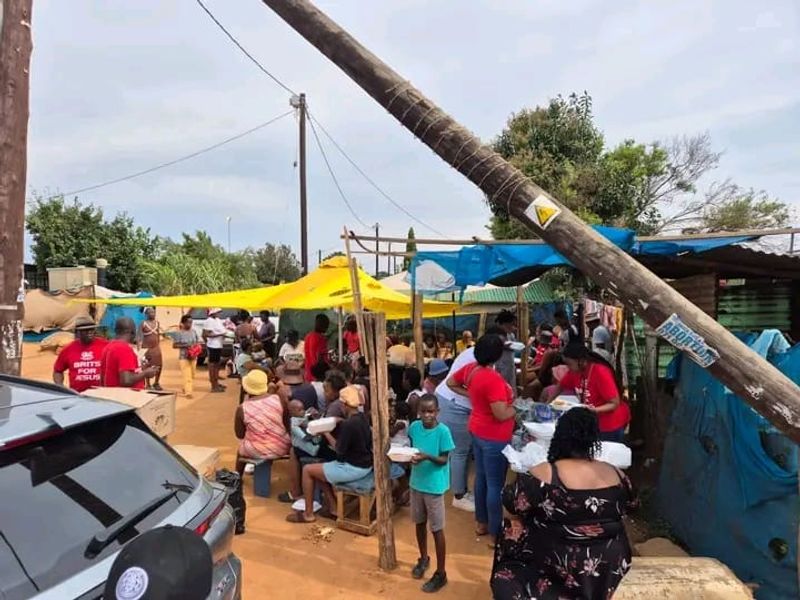 Community members gather for food and prayer during the Gate of Life Church outreach at Plot 89.