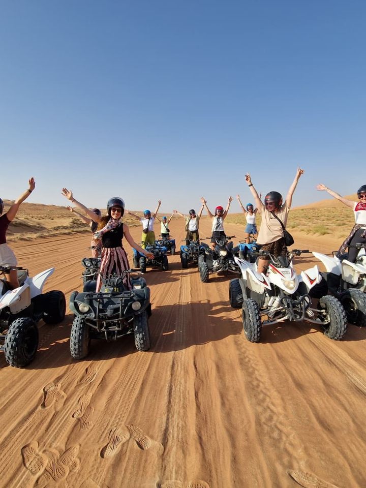Tour group cheering on quad bikes across desert dunes on an Undiscovered Destinations Oman trip