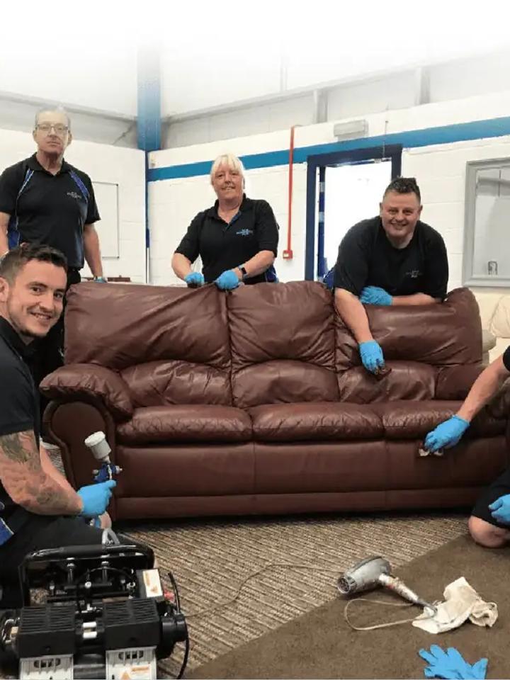 Leather Xpert team in matching polos restoring a brown leather sofa in their workshop