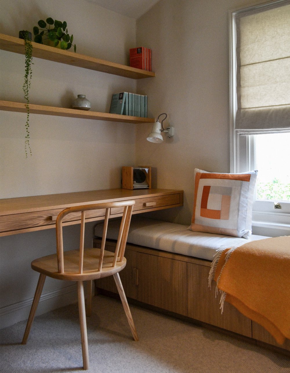 Study with a built-in oak desk and window seat, floating shelves above and a spindle-back chair