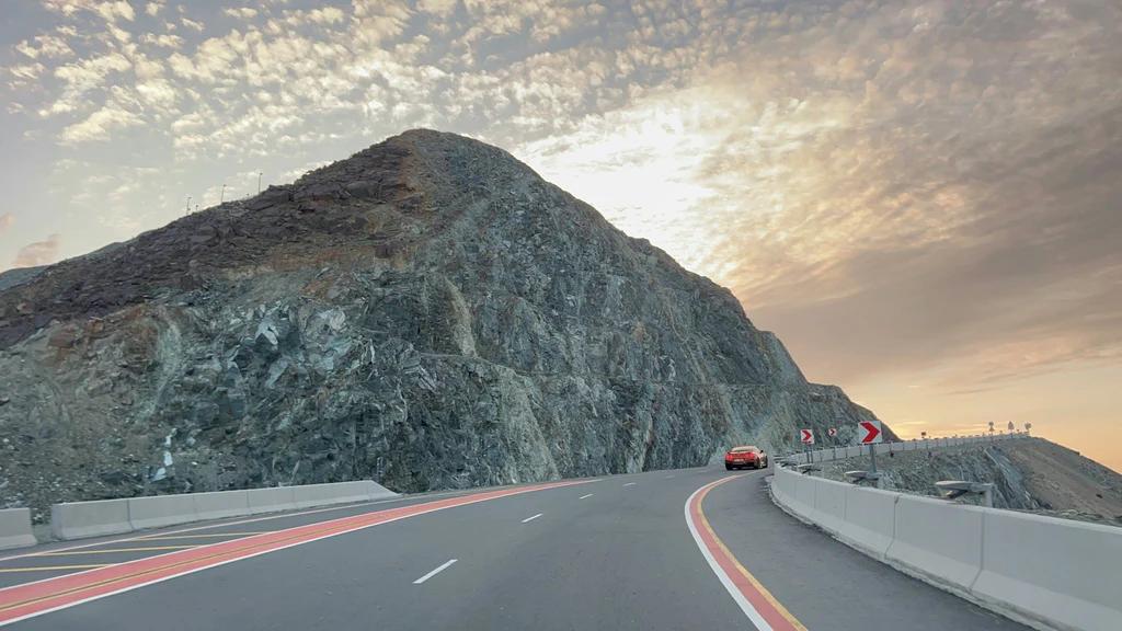 Car driving on a highway next to a mountain Fujairah, United Arab Emirates