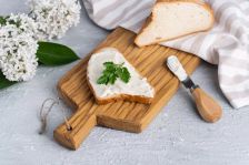 Krajíc chleba s pomazánkou na dřevěném prkénku