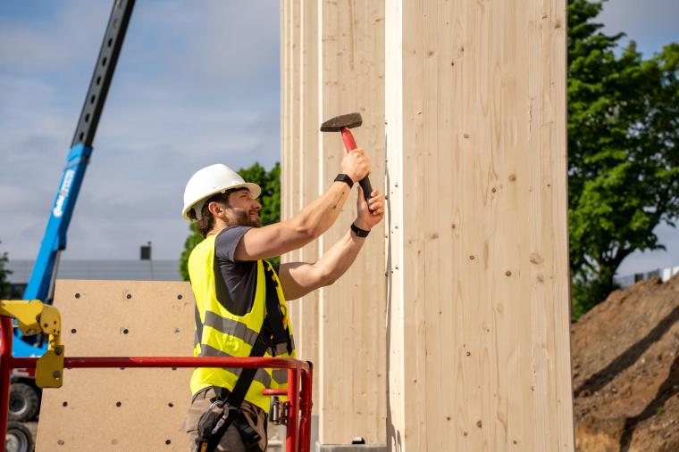 Monteur auf der Hebebühne an einer Holz-Rohrstütze