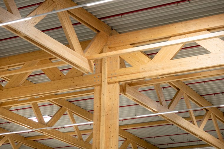 Detailaufnahme eines Knotenpunkts im Holztragwerk: Brettschichtholz-Stütze trifft auf Fachwerkträger, Schraubenverbindungen gut sichtbar.