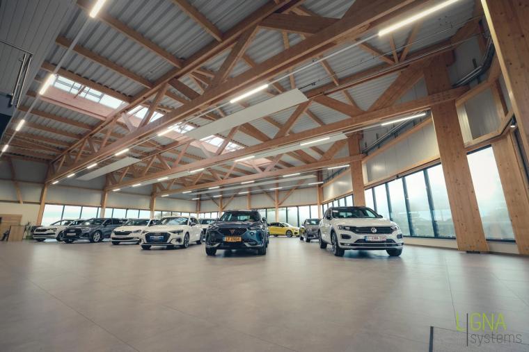 Weitwinkelblick in den Showroom mit voll sichtbarem Fachwerk-Holzdach und Lichtbändern