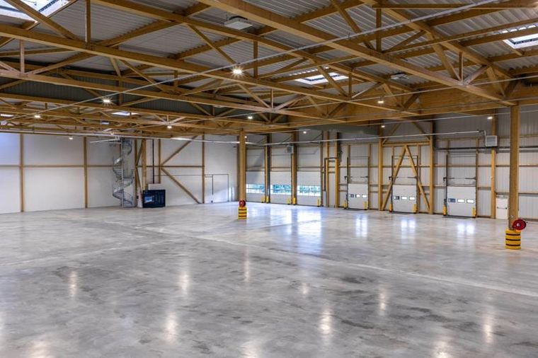 Innenraum der Halle mit Brettschichtholz-Fachwerkträgern, Wendeltreppe und Verladetoren