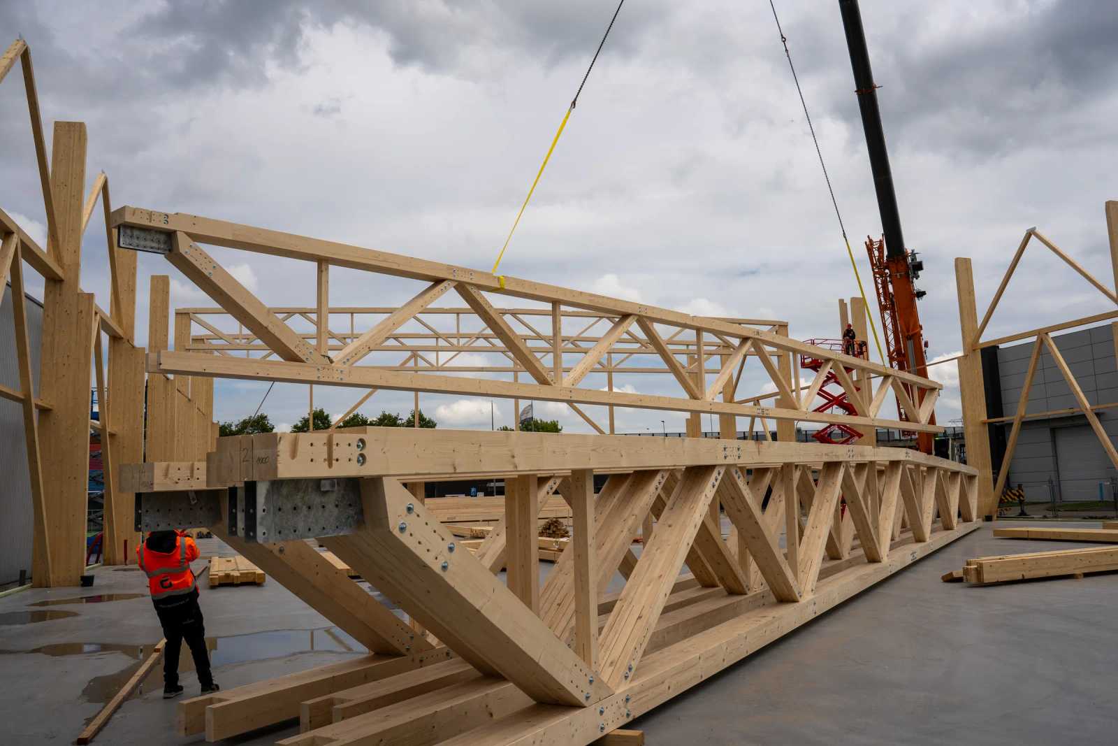Einzelner Holz-Fachwerkbinder am Kran beim Hub auf der Baustelle