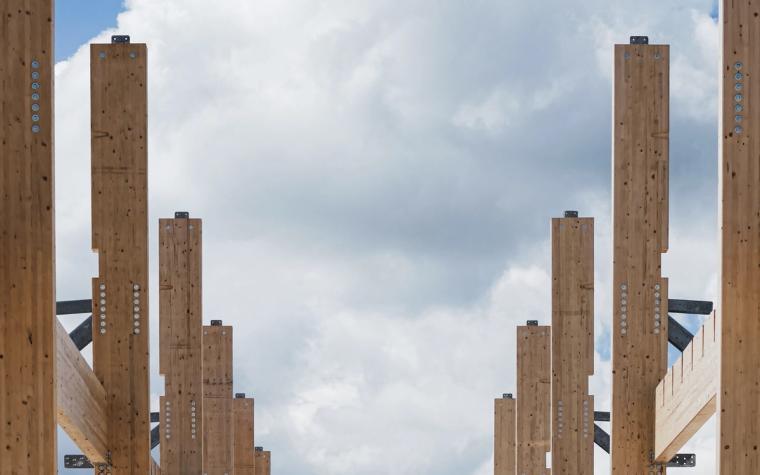 Reihe hoher Brettschichtholz-Stützen vor bewölktem Himmel