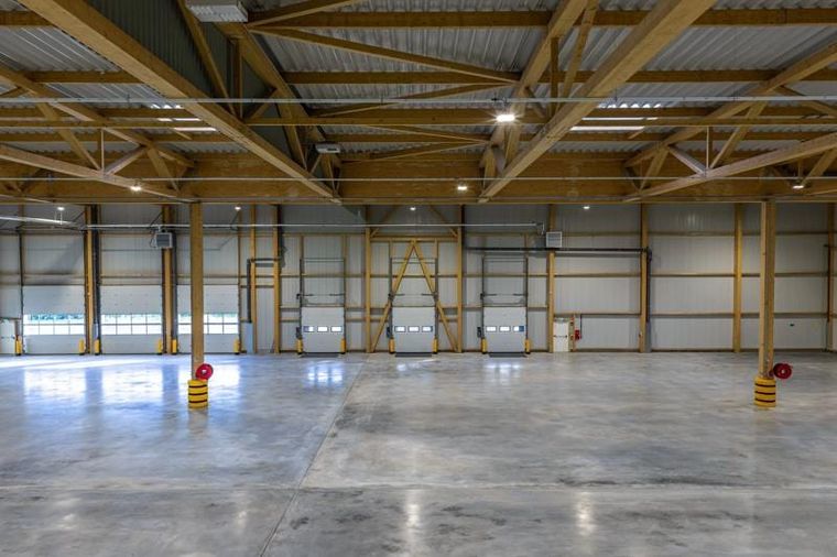 Halleninnenraum mit Holzstützen, Fachwerkträgern und Verladetoren