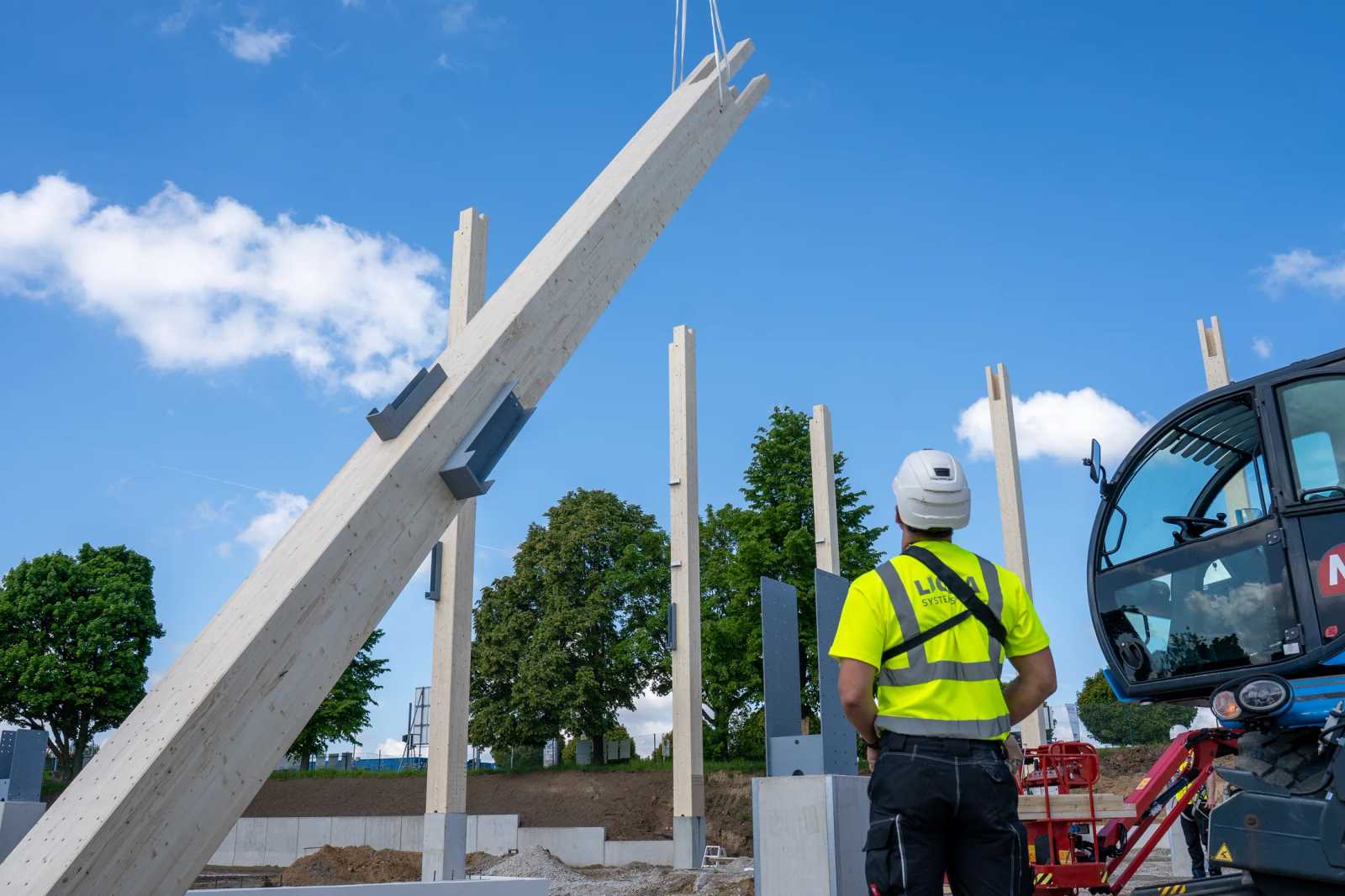 Holz-Rohrstütze am Kran gegen blauen Himmel, Aufrichten auf der Baustelle