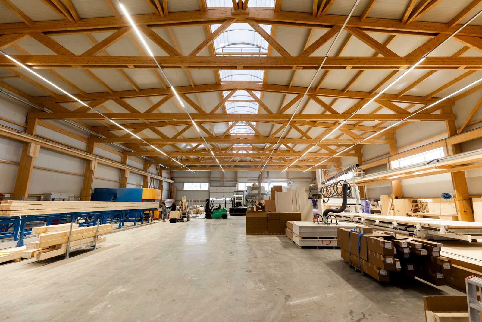 Completed commercial hall with exposed glulam lattice trusses and ridge skylight, column-free interior