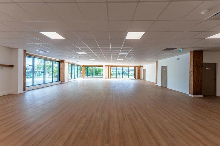 Heller Büroraum mit Holzboden, raumhohen Fenstern und sichtbaren Holzstützen