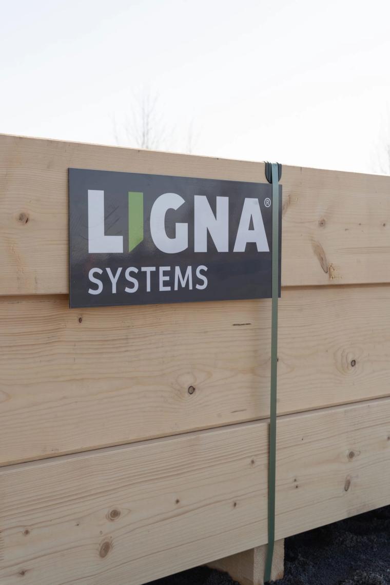 Poutre en bois lamellé-collé portant la plaque « LIGNA systems » sur le chantier