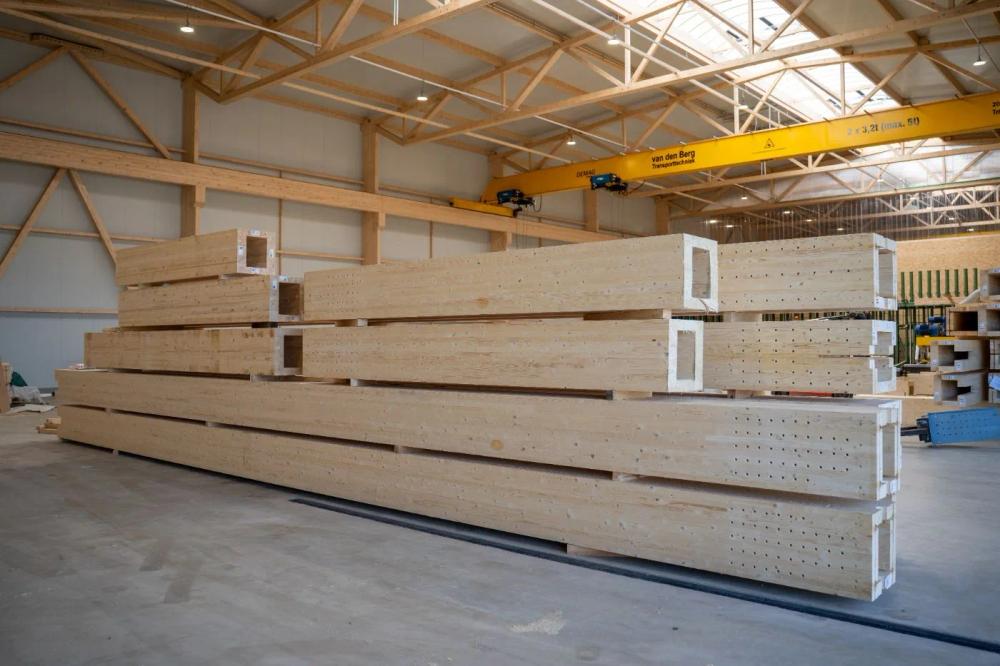 Fertige Holz-Rohrstützen mit hohlem Kastenquerschnitt, gestapelt in der Produktionshalle von LIGNA systems unter der Kranbahn