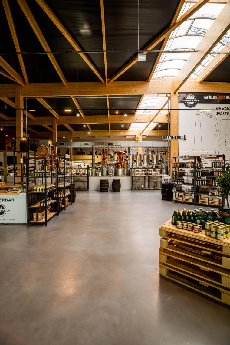 Verkaufsraum mit Produktregalen und poliertem Boden, darüber das Holz-Sparrendach mit Oberlichtern