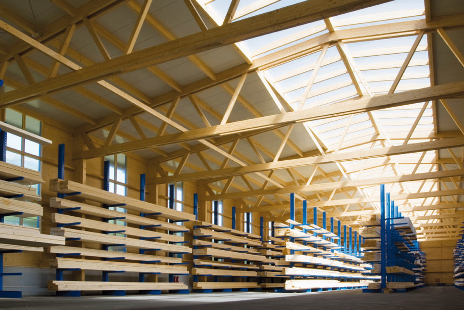 Holzhalle mit mehrgeschossigen Hochregalen unter weitgespanntem Holzdachtragwerk, Lagernutzung