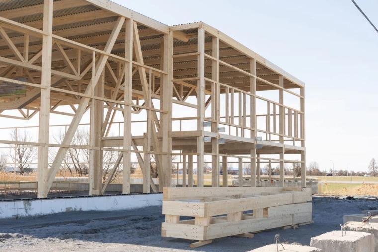 Ossature autoportante du bâtiment commercial devant un ciel bleu, poutres en bois empilées au premier plan