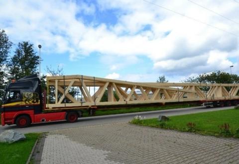 Truck carrying a timber truss to the construction site