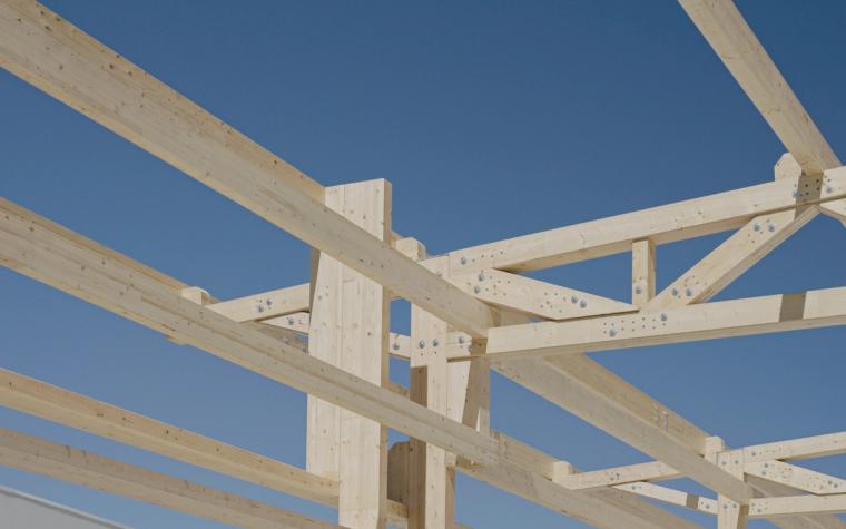 Knotenpunkt eines Fachwerkträgers aus Brettschichtholz vor blauem Himmel