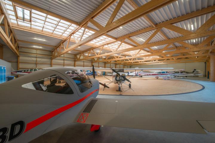 Holztragwerk eines Flugzeughangars mit abgestelltem Flugzeug, Innenansicht