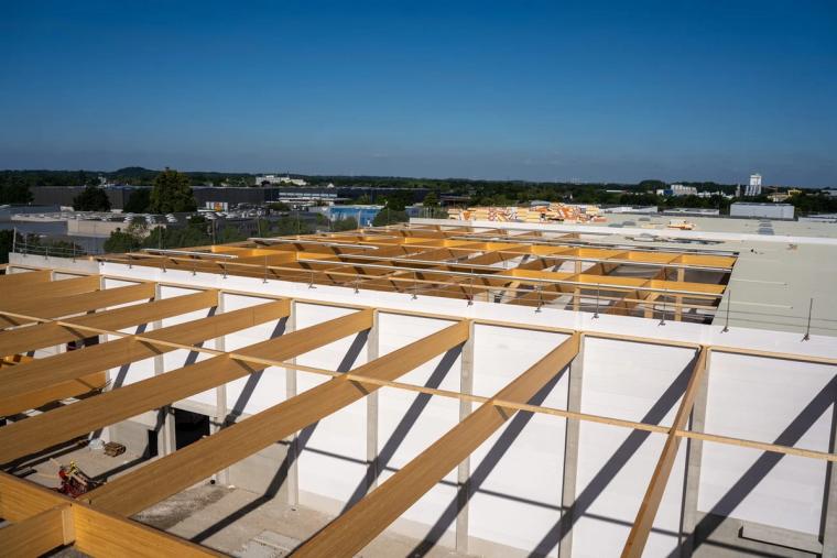 Blick über das Dachtragwerk aus Holz auf die bereits eingedeckte Dachfläche und das Gewerbegebiet von Mönchengladbach
